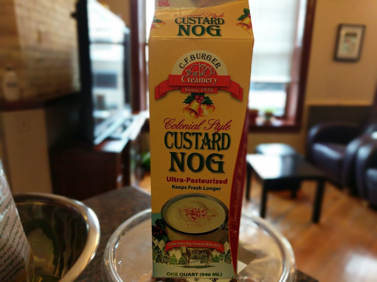 A carton of C.F. Burger Colonial Style Custard Nog behind two empty glasses