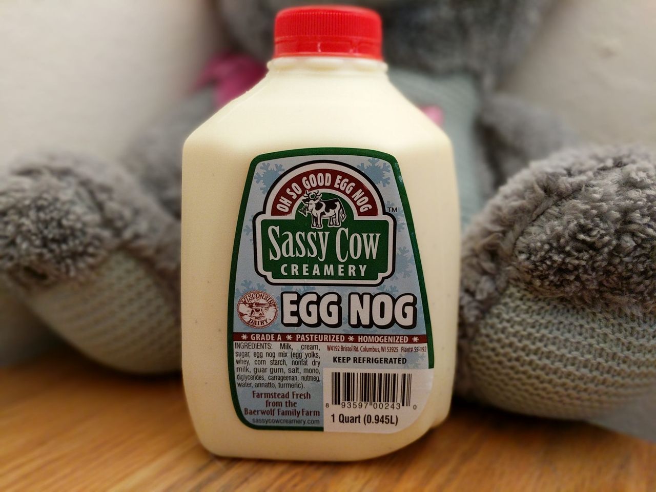 A quart jug of Sassy Cow Creamery Egg Nog in front of a gray plush toy